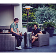 Two men sitting on a patio with a patio heater between them