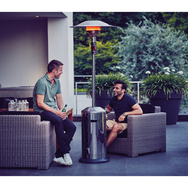 Two men sitting on a patio with a patio heater between them